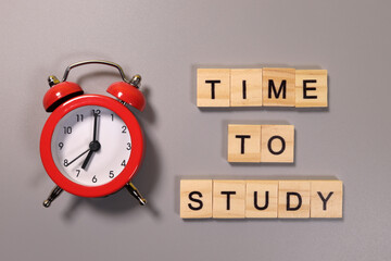 Time to study inscription and alarm clock on gray background
