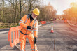 Builder knocking down road setting out steel pins with lump hammer during roadworks. Builder hammering steel bars down into the asphalt during roadworks