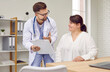 © Studio Romantic - Overweight woman having consultation at doctor's office. Portrait of smiling doctor holding report file with appointment and giving consultation to a fat patient during medical examination in clinic.