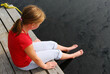 Young girl dipping feet in the lake from the edge of a wooden boat dock