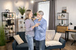 © sofiko14 - Adoring mature couple dressed in casual outfit enjoying slow dance to romantic music at home. Devoted partners celebrating wedding anniversary. Concept of unconditional love and happy family life.
