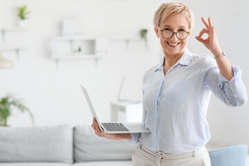 Canvas Print - Mature psychologist with laptop showing OK in office