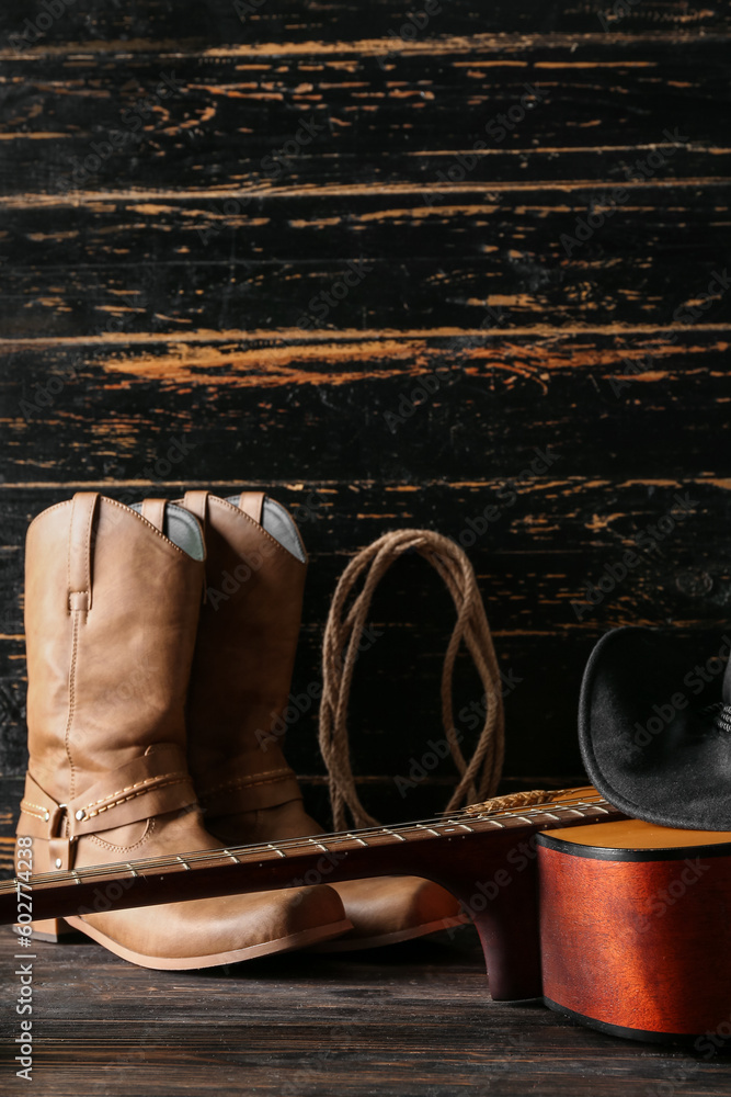 Cowboy hat, guitar and boots on wooden background