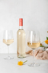 Bottle and glasses of dandelion wine on white table