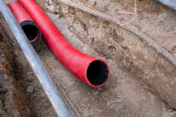 Wall Mural - Red corrugated pipe are buried underground on the street made for electric cable infrastructure installation. Construction site with A lot of supply energy Cables