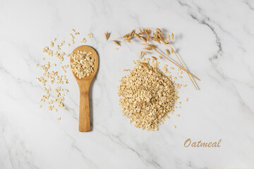 Wall Mural - Oatmeal on wooden spoon. Raw rolled oat grains scattered on marble table. Oat flakes