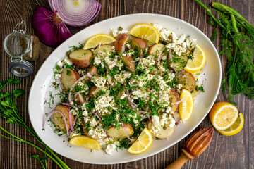 Wall Mural - Greek Potato Salad with Feta Cheese, Fresh Herbs, and Lemon Wedges: Baby red potatoes topped with feta, dill, capers, and extra virgin olive oil