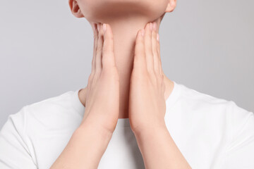 Poster - Woman with sore throat on light grey background, closeup