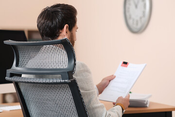 Wall Mural - Man working with documents at wooden table in office, back view