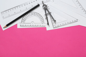 Wall Mural - Different rulers, pencil and compass on pink background, flat lay. Space for text