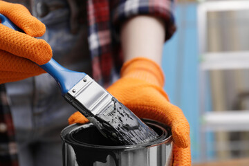 Sticker - Woman dipping brush into can of black paint indoors, closeup