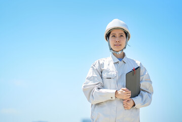 ヘルメットを装着して作業着を着た女性