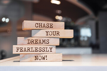Wall Mural - Wooden blocks with words 'Chase your dreams fearlessly now'.