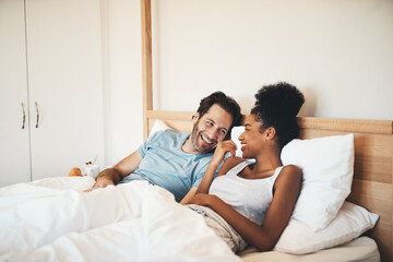 Sticker - Interracial couple, laughing and relax on bed for morning bonding, funny relationship or joke at home. Happy woman and man with smile, laugh and lying in bedroom for fun talk or conversation indoors