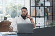 © Patrick S/peopleimages.com - Laptop, phone call and notebook with a business man at his desk in the office for communication or networking. Computer, mobile and writing with a male employee working online for company negotiation