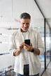 © Stock 4 You - Vertical portrait of middle aged Latin or Indian business man using phone mobile technology application for online work communication. Smiling mature Hispanic businessman holding smartphone in office.