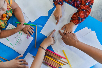 Wall Mural - Creative kids during an art class in a daycare center or elementary school classroom drawing with female teacher.