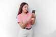 A portrait of a happy Asian woman is wearing pink t-shirt and holding her phone, isolated by white background