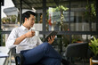 © bongkarn - An Asian businessman focuses on reading a book while sipping his morning coffee