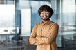 © Liubomir - Portrait of a young Indian designer, programmer, businessman standing in the office wearing glasses and a blue shirt, arms crossed, smiling at the camera