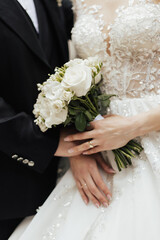 Wall Mural - Cropped shot of bride and groom are hugging at the wedding day in the garden. Bride holding the beautiful and luxurious bouquet of fresh white flowers.