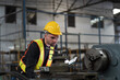 © amorn - Male engineer worker working and inspecting parts quality of lathe machine in industry factory, wearing safety uniform, helmet. Male technician worker maintenance parts of machine in workshop