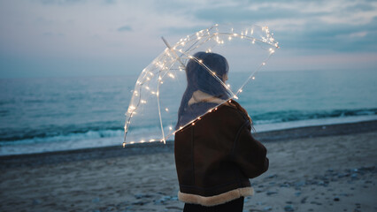 Wall Mural - Glowing umbrella of a girl walking on the beach in the night outdoor