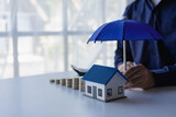 Fototapeta Kawa jest smaczna - insurance business The agent spreads the umbrella on the house. The concept of preventing health accidents and natural disasters, a close-up image.