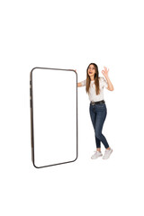 Recommending mobile app, caucasian girl leaning on big smartphone with empty white screen showing ok sign gesture recommending mobile app. Cheerful excited girl standing near huge mobile phone mockup.