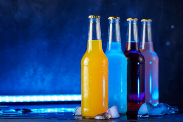 Wall Mural - fruit and berry mix cocktails or sodas on a blue background. cold bottles of summer drinks