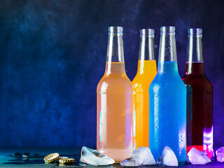 Wall Mural - bottled cold berry and fruit soda. blue background. cold summer drinks. ice cubes, copy space