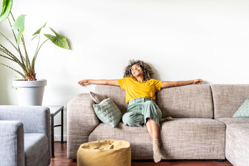 happy afro american woman relaxing on the sofa at home - smiling girl enjoying day off lying on the 