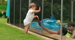 © Marco - Baby looking at kids play inside swimming pool water during sumemr day. infant leaning on pool fence