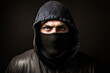 © MVProductions - Mugshot of burglar wearing a balaclava closeup on black dark background. Portrait of thief burglar in a black hoodie and mask. Generative AI