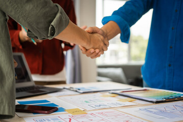 Wall Mural - shaking hands, group of asian creative team programing designers participate in all phases of the ux