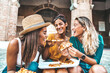 © Davide Angelini - Three young female friends eating pizza sitting outside - Multiracial women enjoying street food in the city - Italian food culture and summer vacations concept