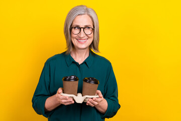 Sticker - Portrait of cheerful lovely lady hands hold fresh coffee order look empty space isolated on yellow color background