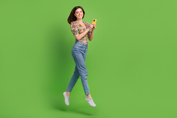 Canvas Print - Full length portrait of charming energetic person jumping use smart phone empty space isolated on green color background