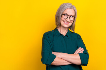 Portrait of minded cheerful corporate lady folded hands look empty space wear green isolated on yellow color background