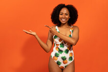 Positive Joyful Black Woman In Swimsuit Showing Something Invisible