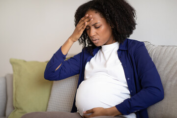 Unhappy millennial african american pregnant lady with big belly suffer from headache and health problems