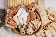 Basket With Baby Stuff And Accessories For Newborn. Gift Basket With Cotton Clothes And Muslin Swaddle Blanket, Baby Shoes, Toys And Cute Teddy Bear In Beige Colors.