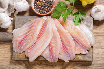 Wall Mural - fresh fish fillet of tilapia with ingredients for cooking, top view