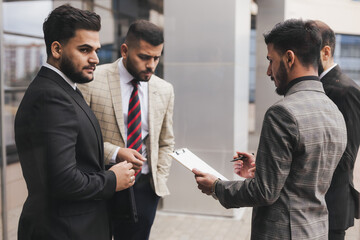 Business people outdoor meeting. A group of business people meet outdoors. Male employees in suits communicate outdoors. Business partners discuss and argue. Relationships and promotion.