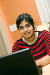 Portrait of Indian teenager working with a laptop conputer