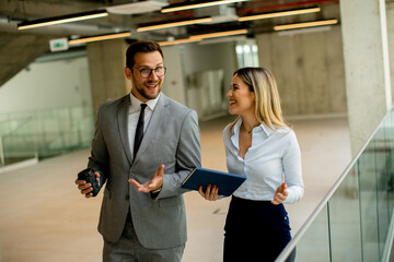 young coworkers walking and talking along corridor in modern office