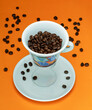 Tasse de café en lévitation sur fond orange avec grains de café