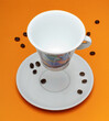 Tasse de café en lévitation sur fond orange avec grains de café
