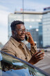 © Jovo Jovanovic/Stocksy - Happy man talking on mobile phone standing outside his car in city