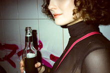Woman In Turtleneck Sweater Party Holding A Transparent Glass Bottle